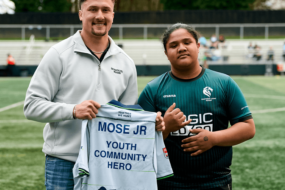 A young Seattle Seawolves supporter celebrates with players at a community event.